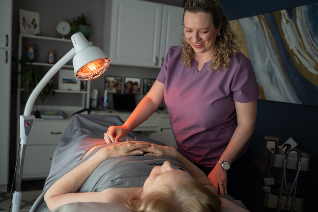 Lidia Esper carefully placing acupuncture needles for a relaxed patient in the bright treatment room at the Brandon clinic